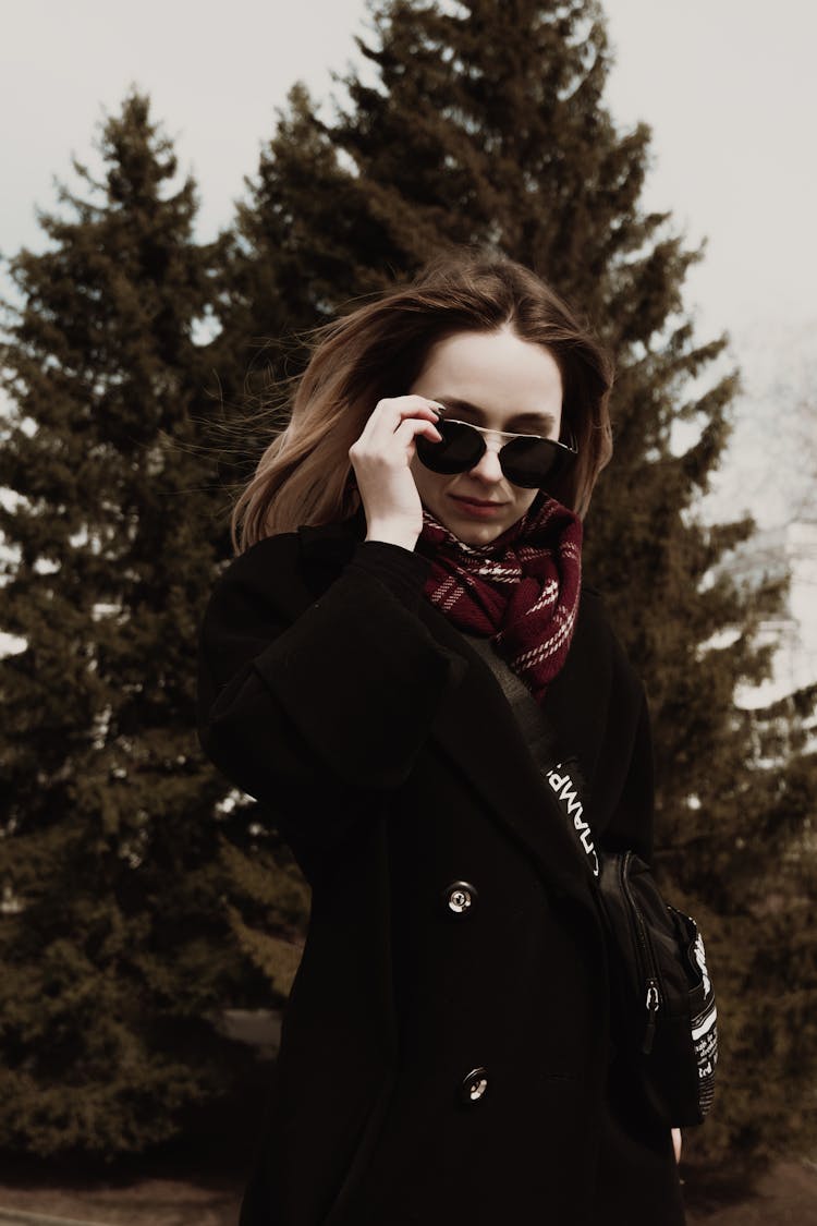 Woman In A Black Coat Taking Off Her Sunglasses