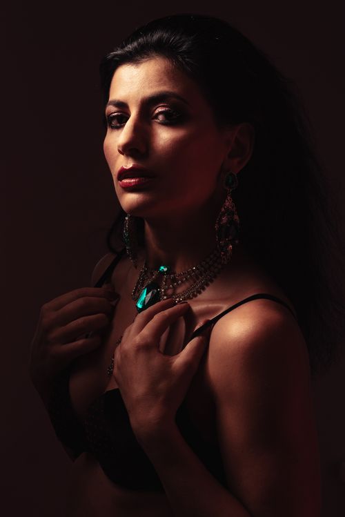 Free Alluring woman with elegant accessories in black underwear looking at camera in darkness Stock Photo