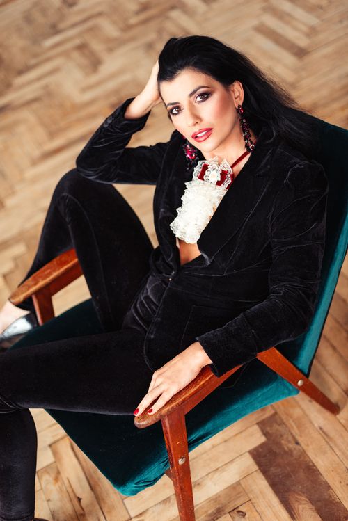 Free From above of confident female with hair hair sitting on chair and leaning on hand against wooden parquet in room in daytime Stock Photo