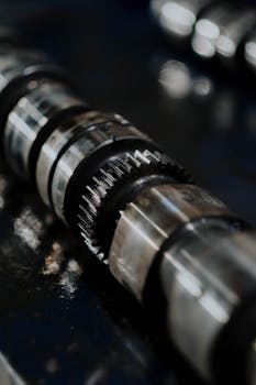 Detailed image of a camshaft showcasing gears and reflections on a dark surface.