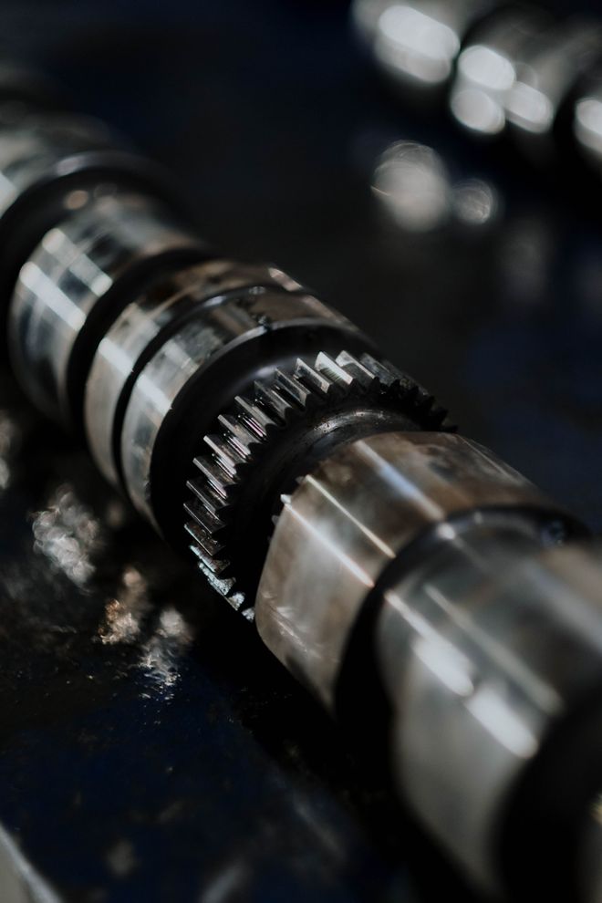 Camshaft and gears reflected on a dark surface. Photo by cottonbro studio on Pexels.