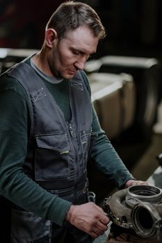 Mechanic focused on inspecting an engine component in a workshop.