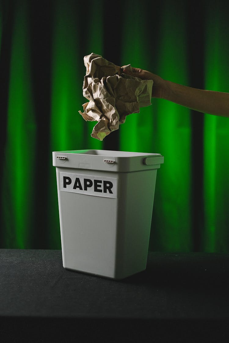 
A Person Throwing A Crumpled Paper In The Trash