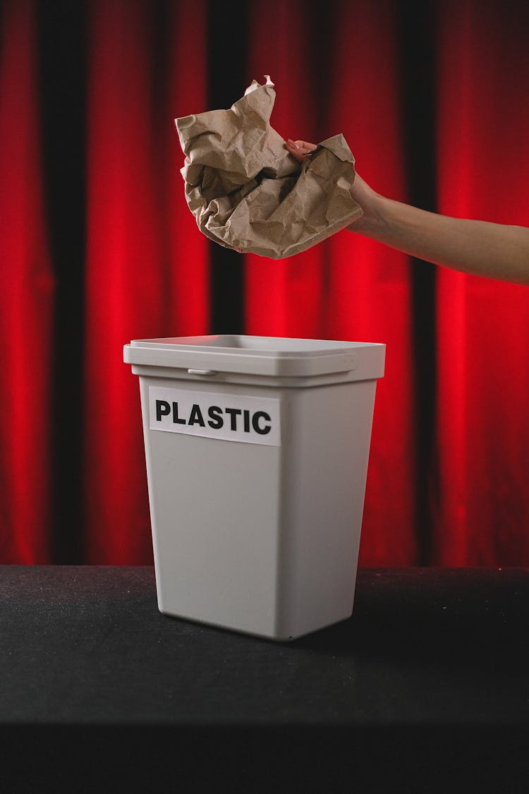 A Person Throwing A Crumpled Paper In The Trash Bin