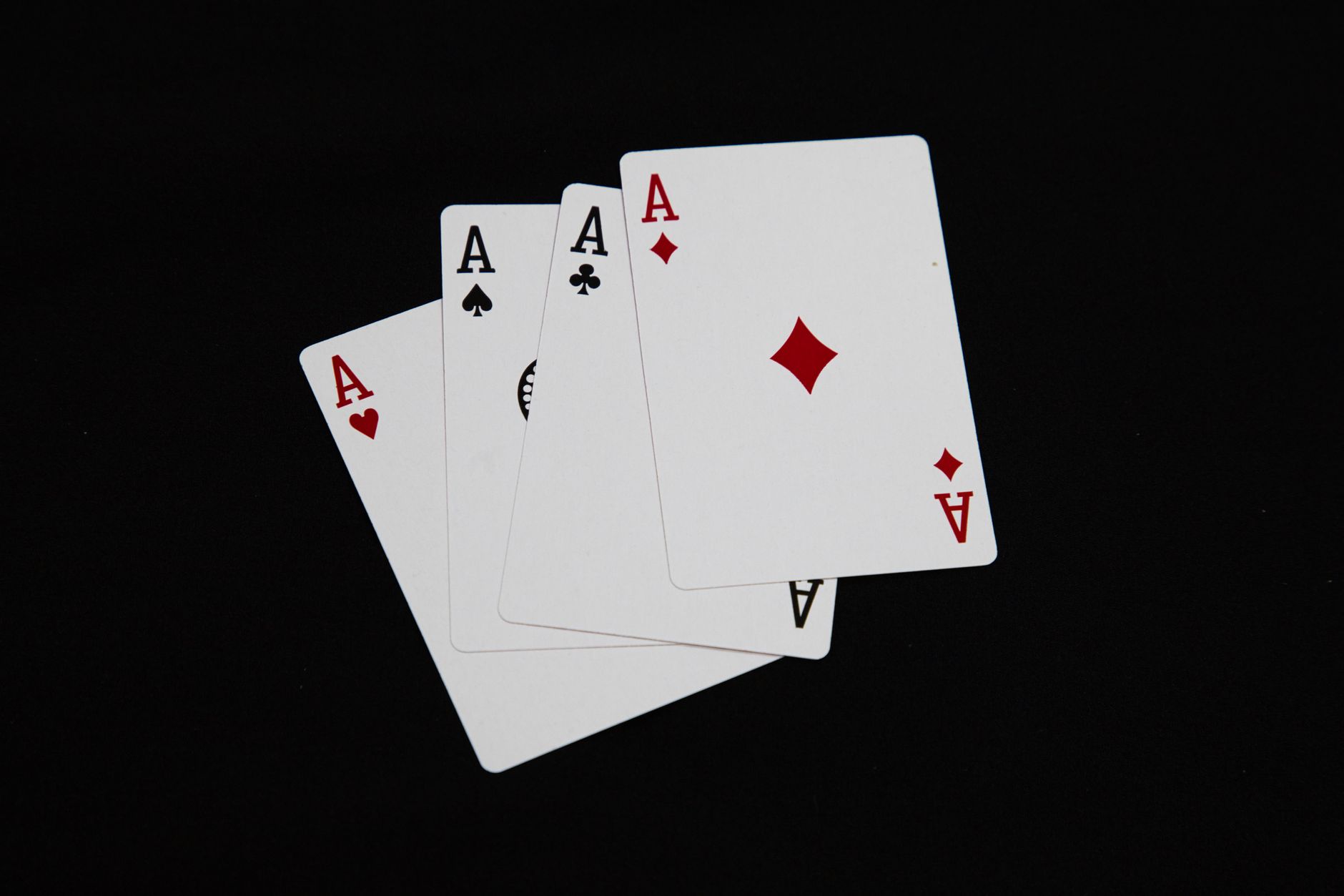 A set of four aces from a deck of playing cards arranged on a black background.