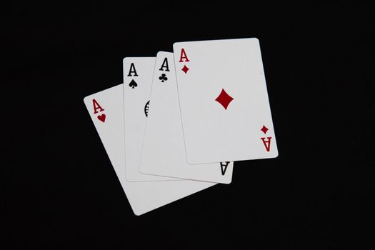 A set of four aces from a deck of playing cards arranged on a black background.