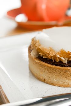 Detailed view of a scrumptious almond tart with icing on a white ceramic plate.