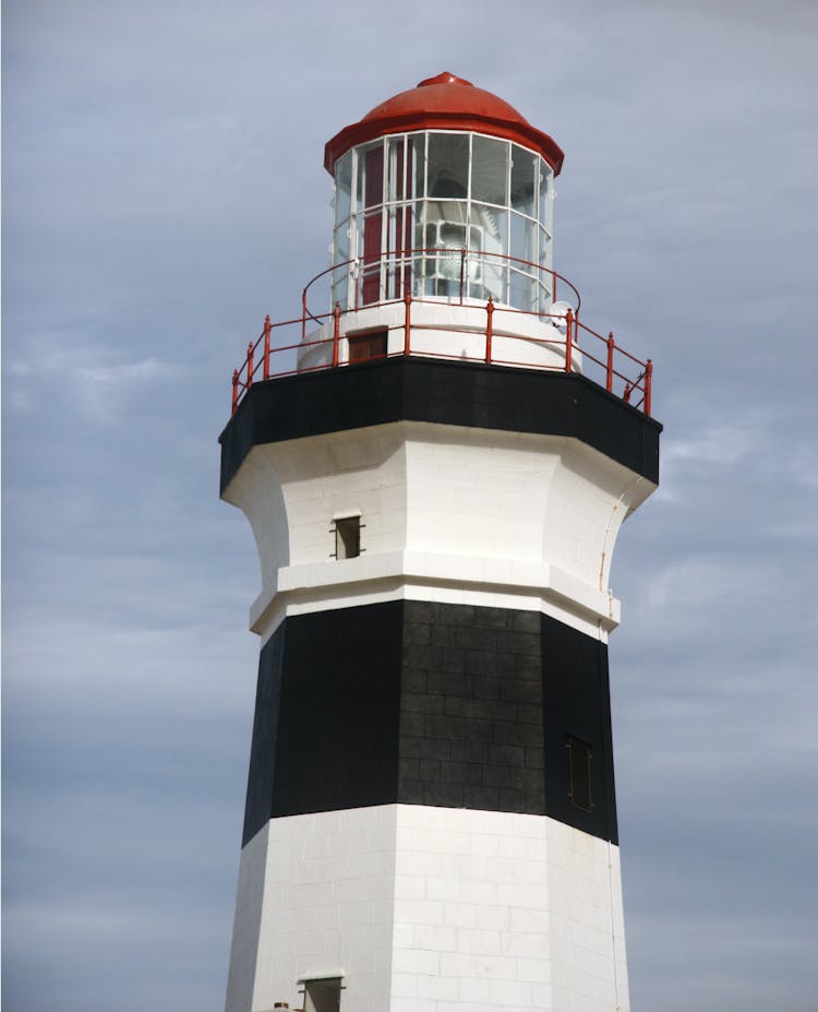 White And Black Lighthouse Under Cloudy Sky