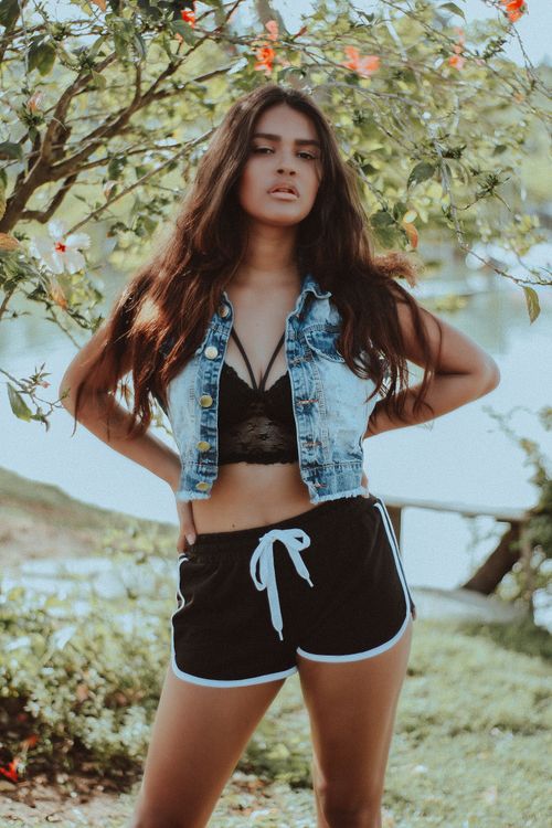 Free Stylish young woman posing in summer attire by a lake, exuding confidence. Stock Photo