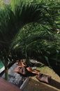 Woman in Brown Leather Jacket Lying on Brown Wooden Board on Swimming Pool