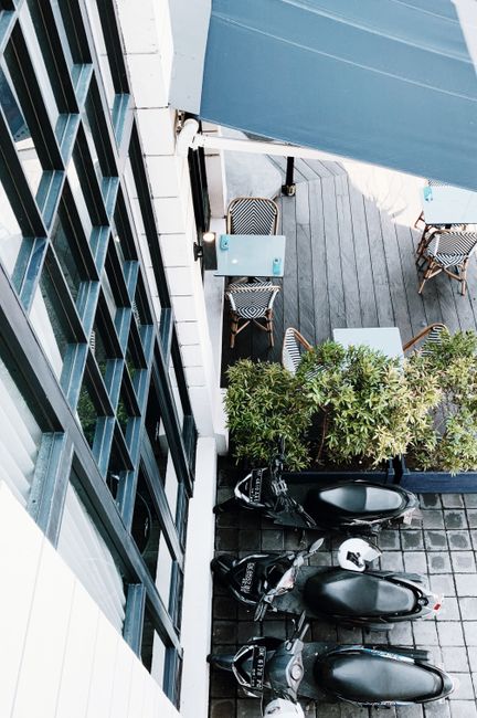 High angle shot of a café terrace with parked motorcycles and outdoor seating.