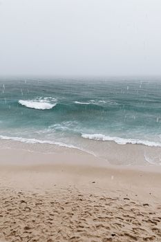 Tranquil seascape with gentle waves and raindrops on a sandy shore. Perfect for relaxation themes.