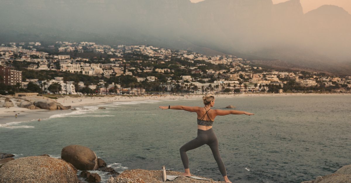 A person doing yoga above the Cape Town coastline at sunset