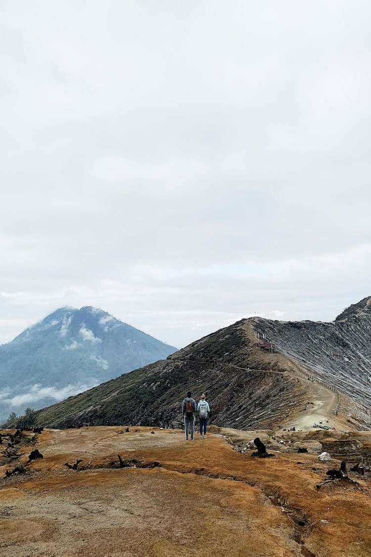 Distant View Of Two Hikers In The Mountains