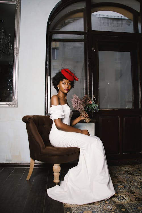 Woman in White Off-shoulder Wedding Dress Sitting in Brown Fabric Sofa Chair