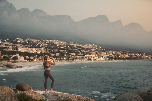 Free Woman overlooking Camps Bay, Cape Town at sunset, with city lights and mountains. Stock Photo