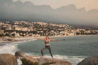A Woman Doing Yoga while Standing on Rock Near Sea