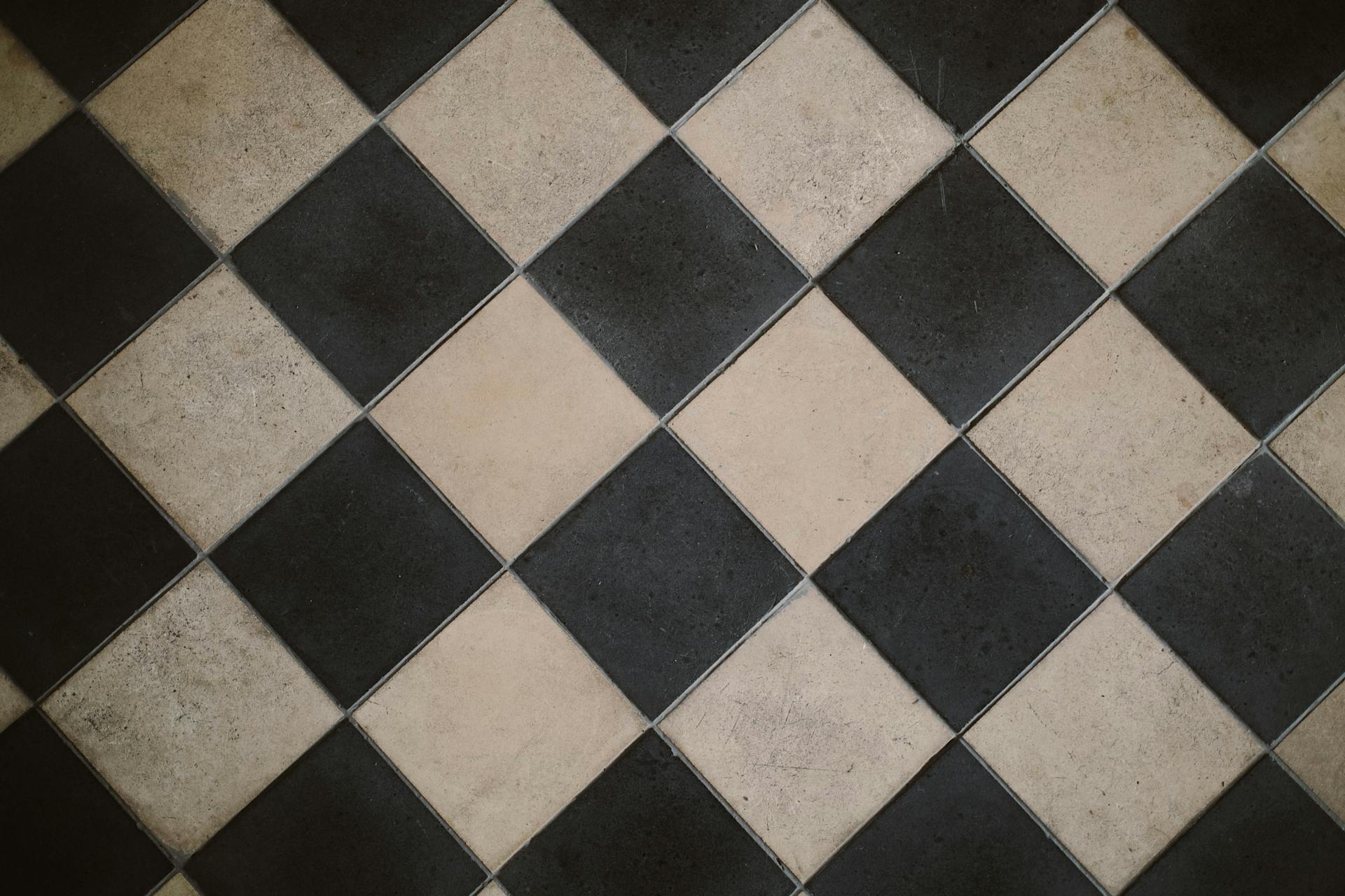 Diagonal black and white checkered floor tiles with a geometric design.