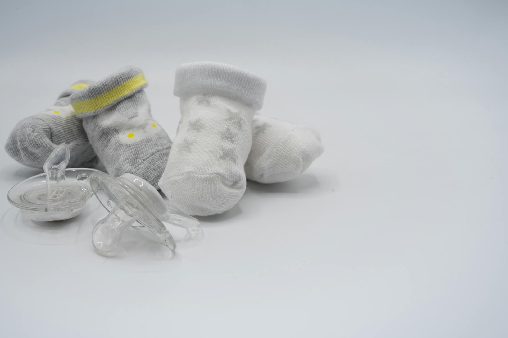 A charming still life of baby socks and pacifiers on a white background, perfect for nursery decor.