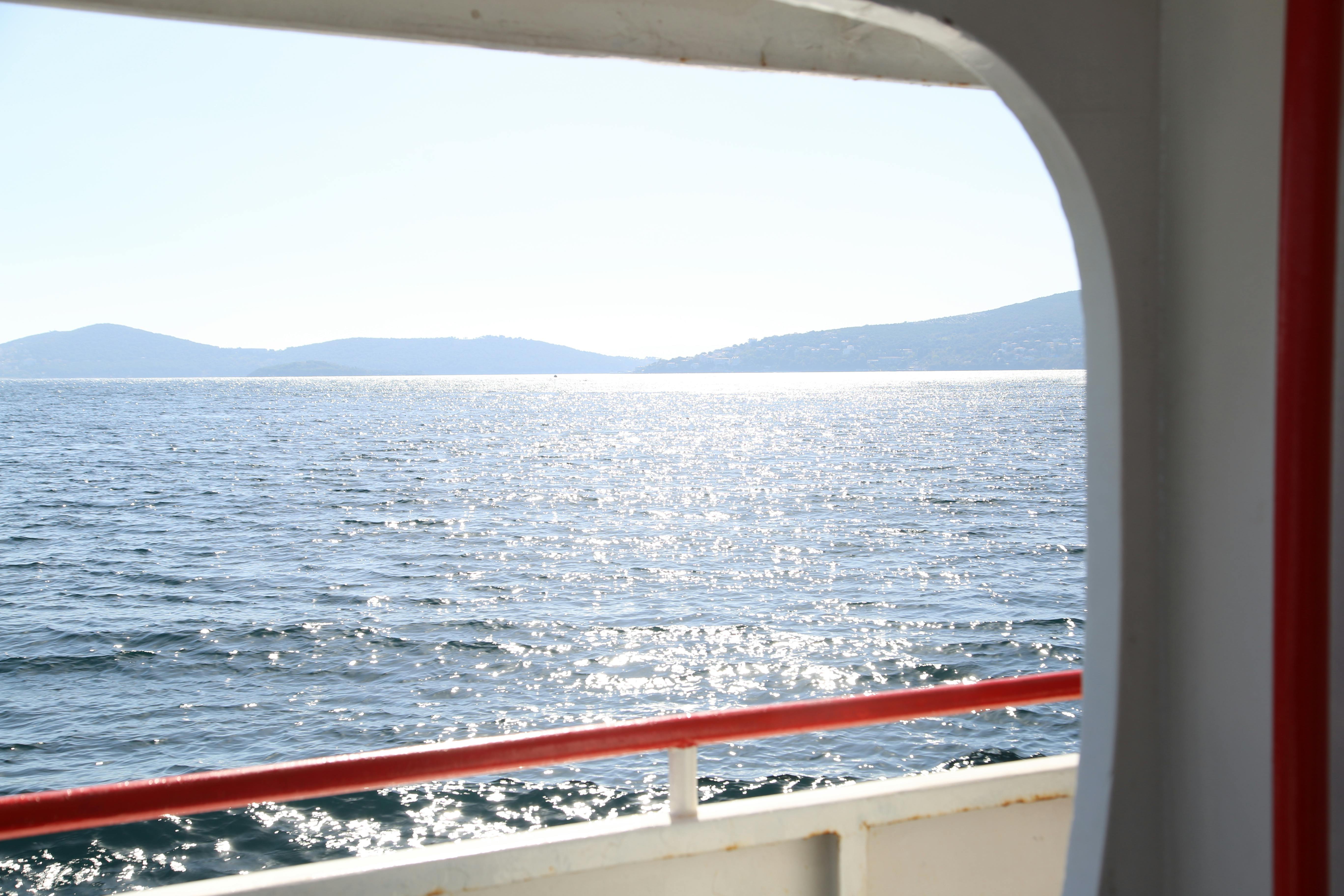 Sparkling sea view from a boat in Adalar, Istanbul, showcasing tranquil waves and distant hills.