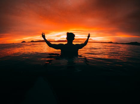 Silhouette of a person at sunset in the ocean in Indonesia, creating a dramatic and serene seascape.