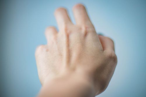 Free Artistic depiction of a blurred hand reaching against a blue background. Stock Photo