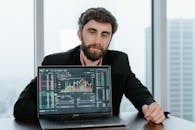 A Man in Black Coat Sitting Behind a Laptop