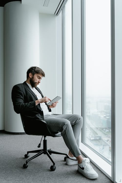  A Businessman Using a Tablet by the Office Window