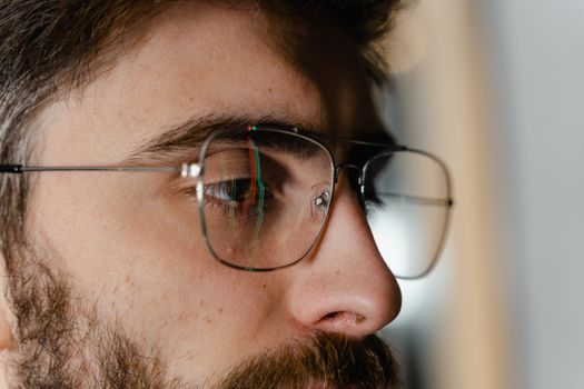 Detailed close-up of a man's side profile with eyeglasses and beard.