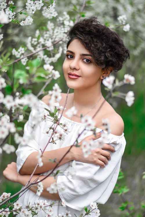 Free Portrait of a woman surrounded by cherry blossoms in spring, exuding elegance and natural beauty. Stock Photo