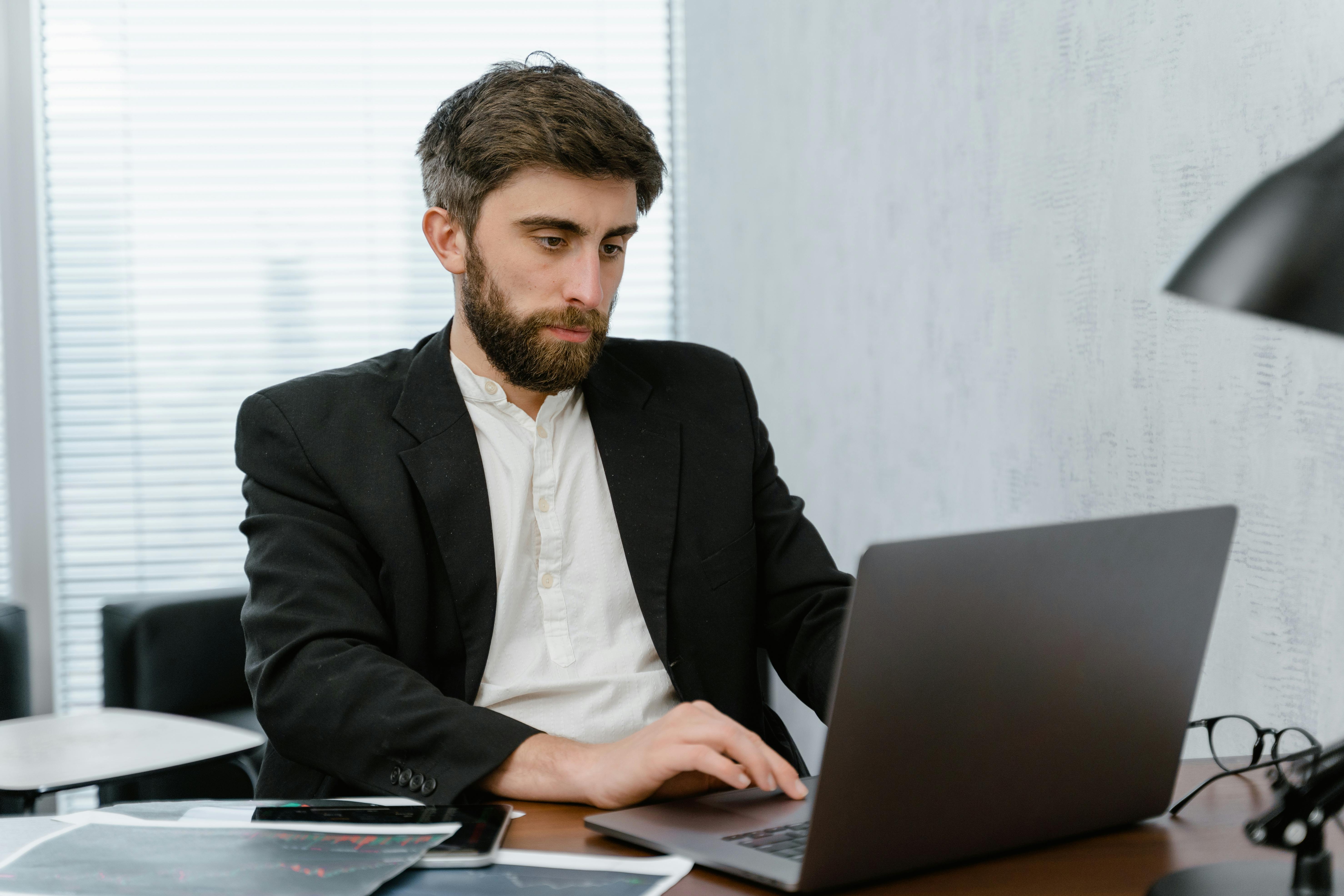 man in black suit jacket using macbook