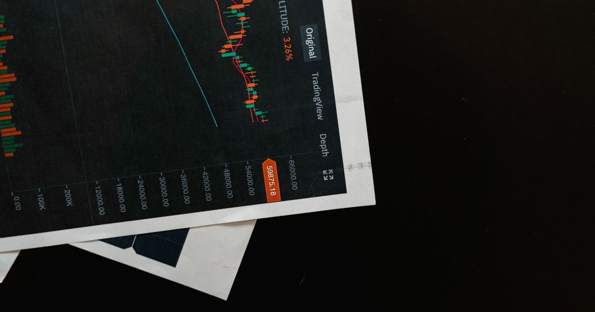 Printed financial charts and market analytics arranged on a dark surface.