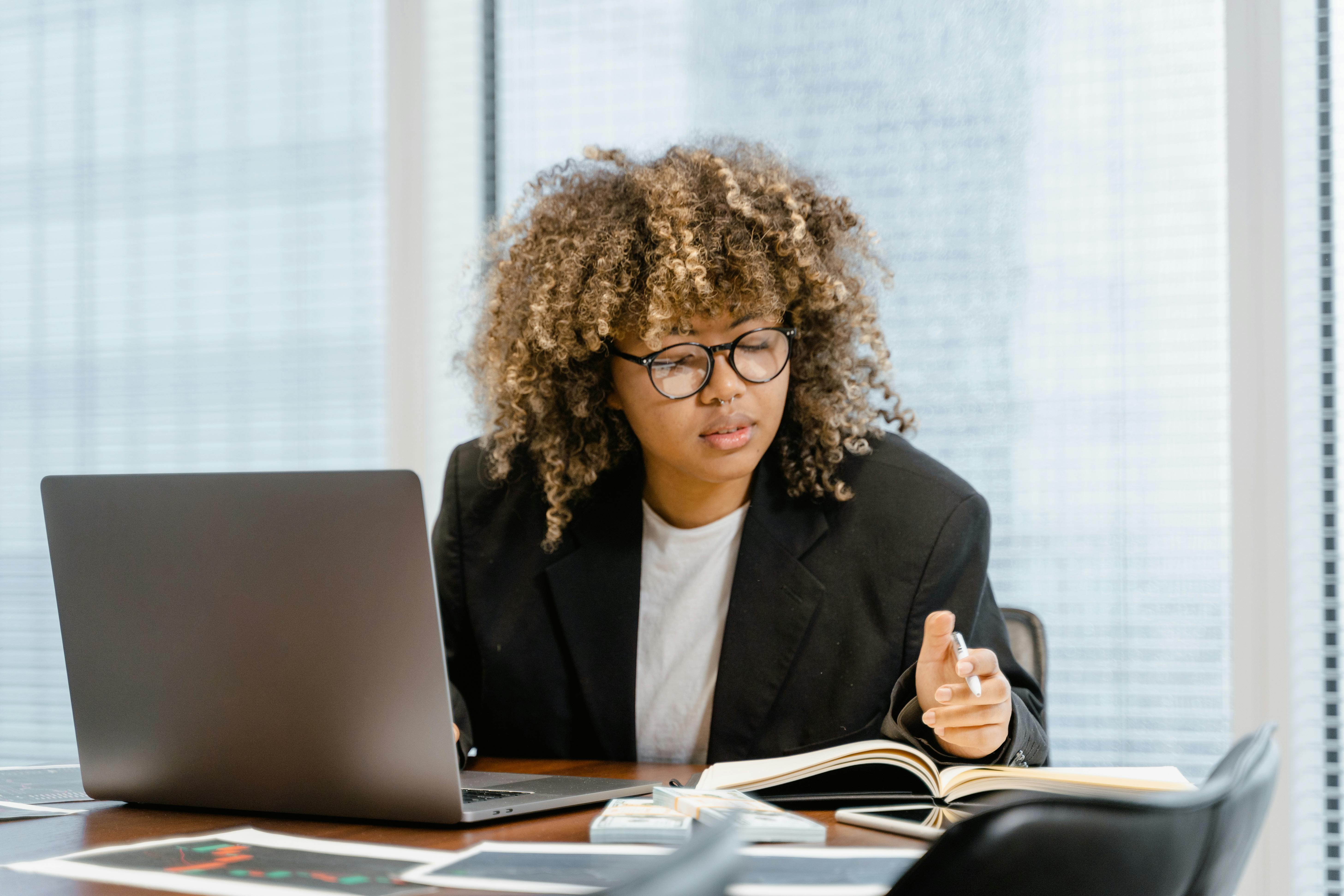 woman in black blazer sitting on chair in front of macbook