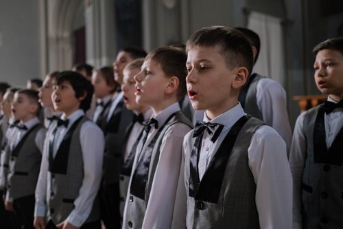 Free Group of boys in choir uniforms singing together indoors during practice. Stock Photo