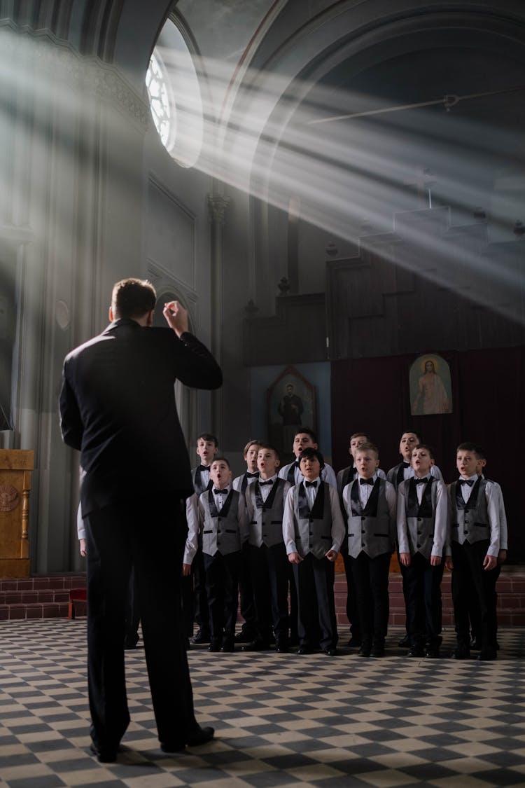 Man In Black Suit Standing In Front Of Kids Singing