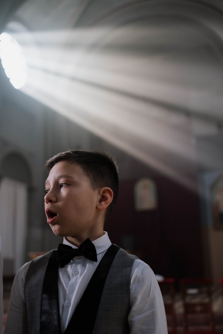 Close-up Photo Of Boy Singing On A Church 