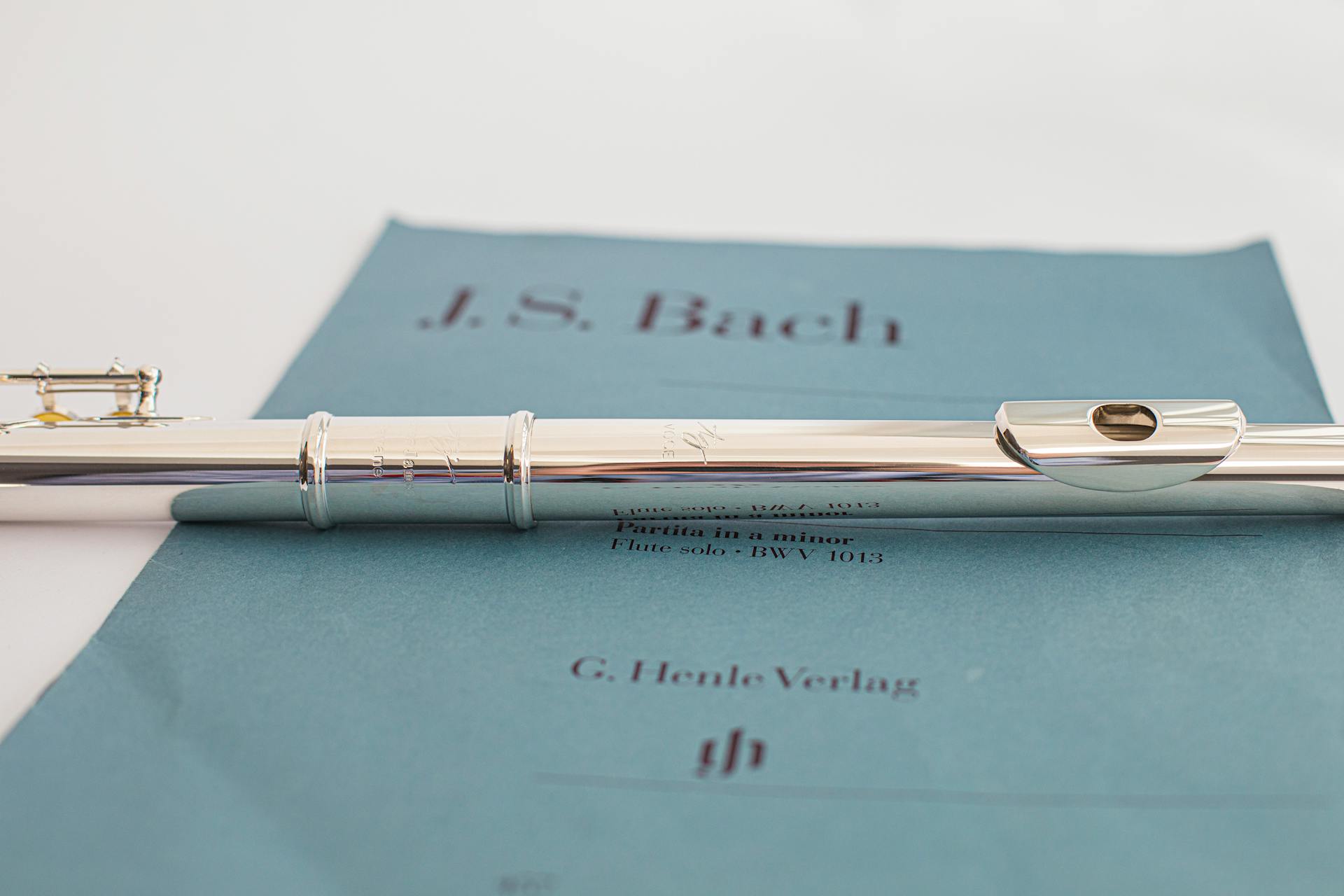 Close-up of a flute resting on J.S. Bach sheet music, capturing elegance and musical artistry.