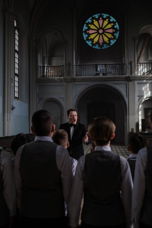 Free Choir Conductor in Black Suit Teaching the Boys Stock Photo