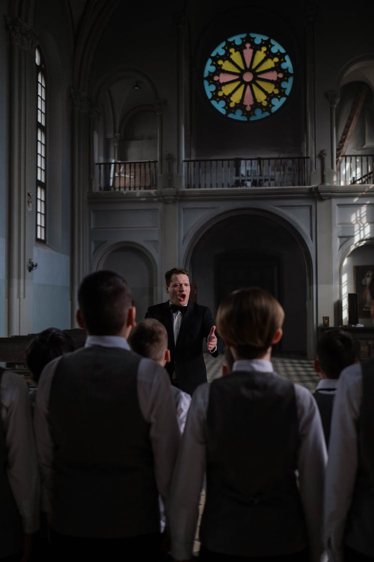 Choir Conductor In Black Suit Teaching The Boys