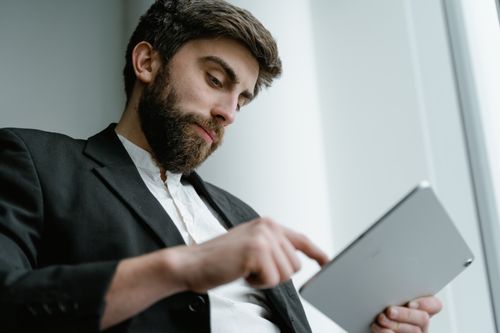 Free Man in formal attire using a tablet inside office. Focus on technology and concentration. Stock Photo