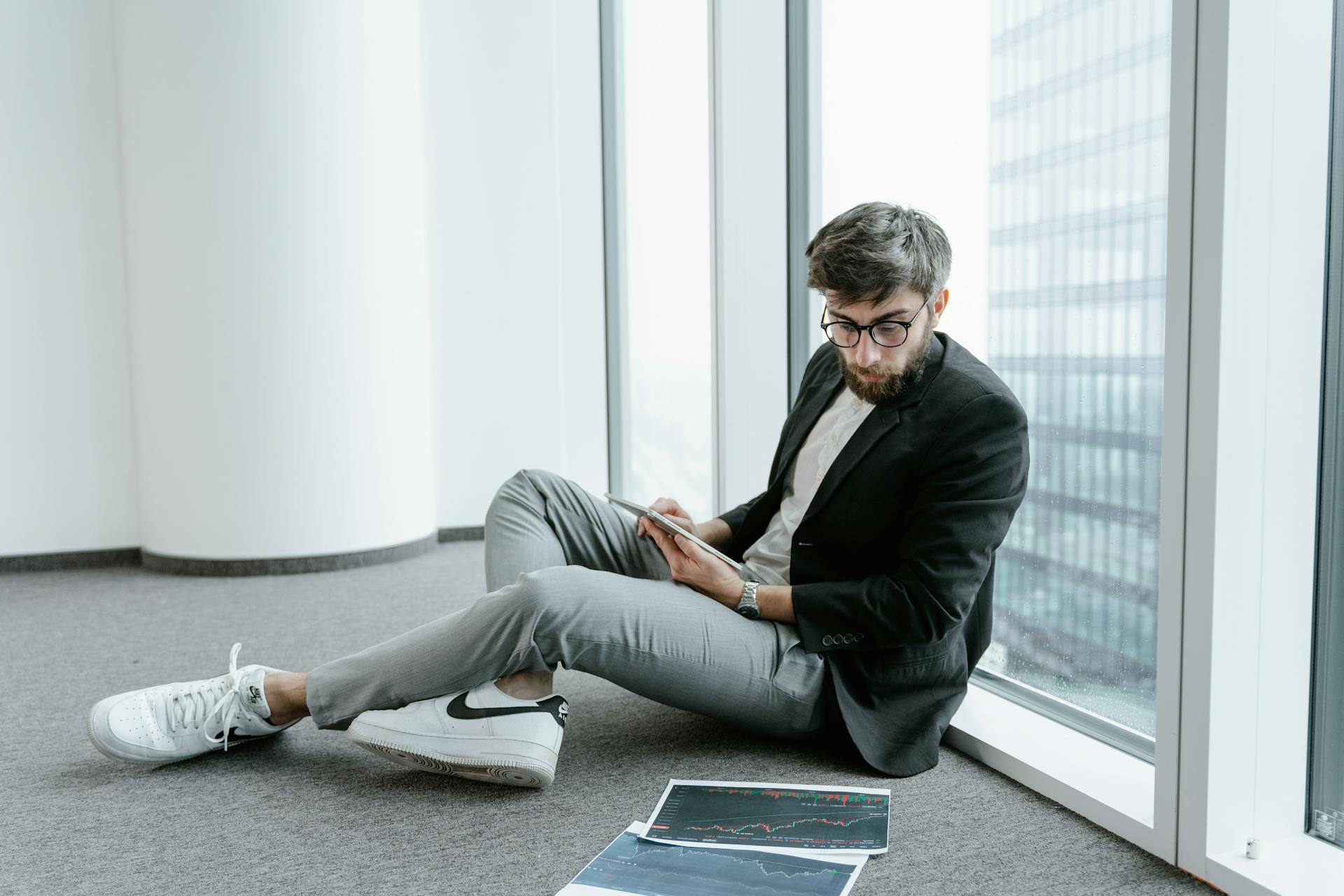 A Man Wearing Black Jacket Looking at Graphs on the Floor