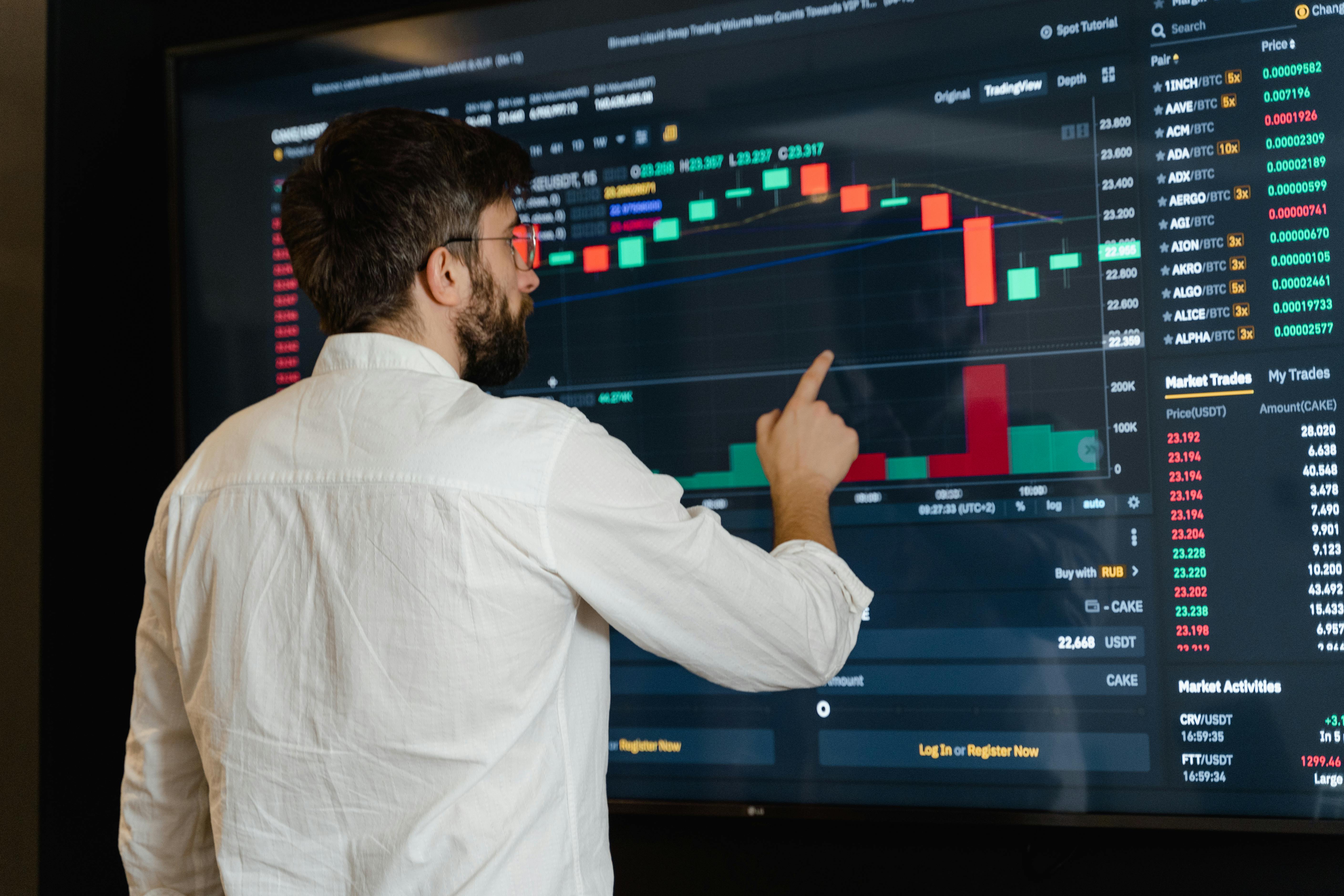 man in white dress shirt analyzing data displayed on screen