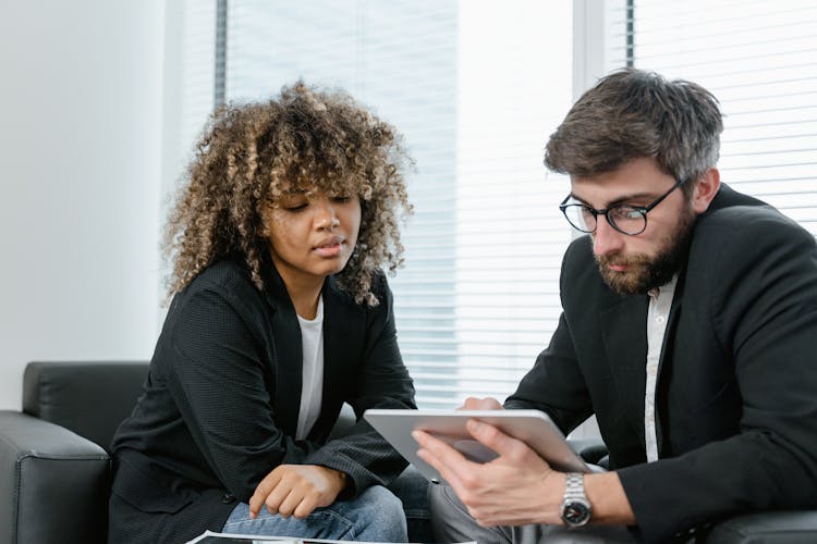 Photo Of A Man And A Woman Looking At A Tablet Together