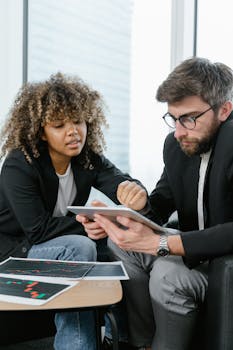 Two professionals discussing work using a tablet during a business meeting.