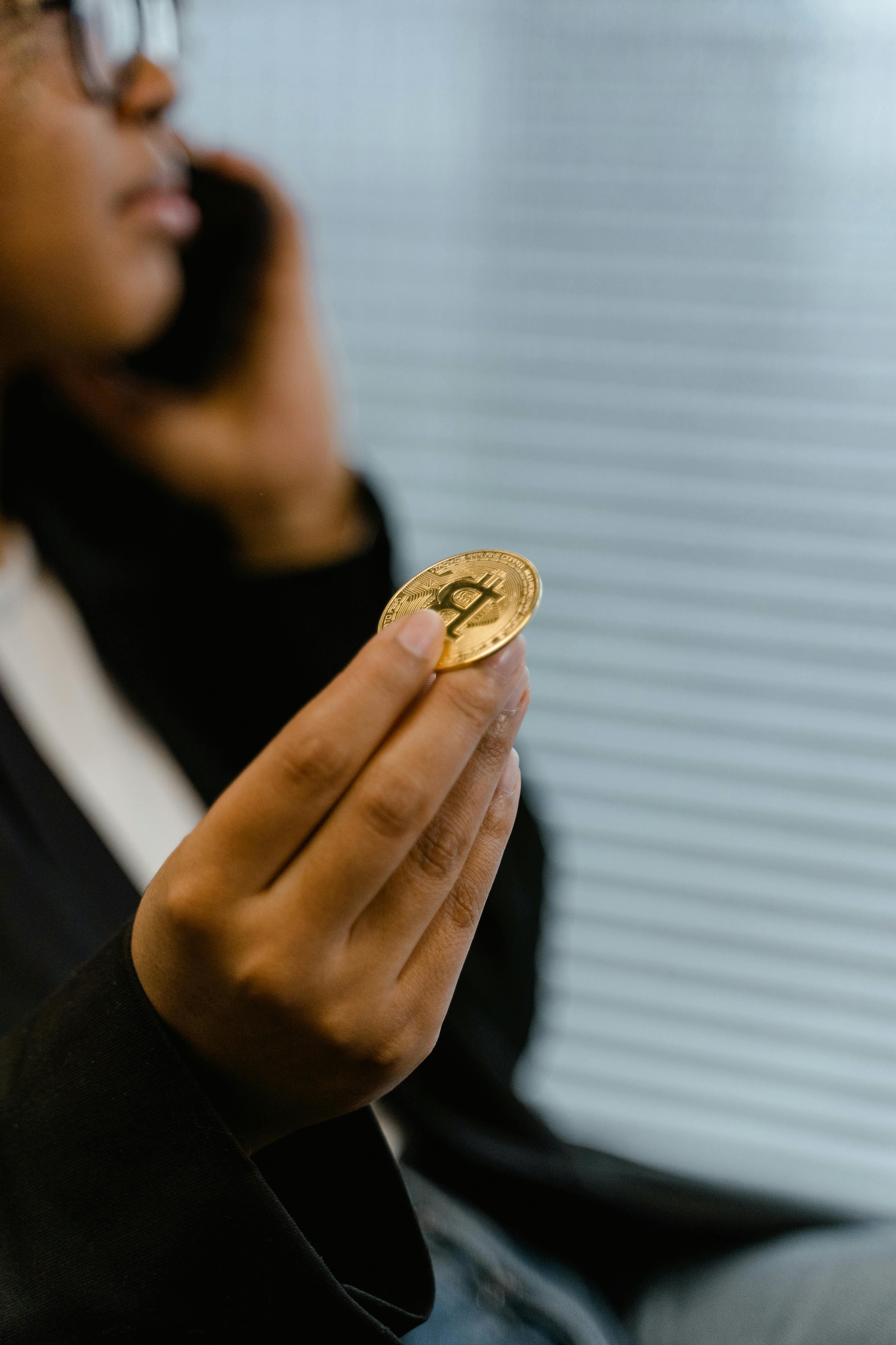 person using cellphone holding a bitcoin