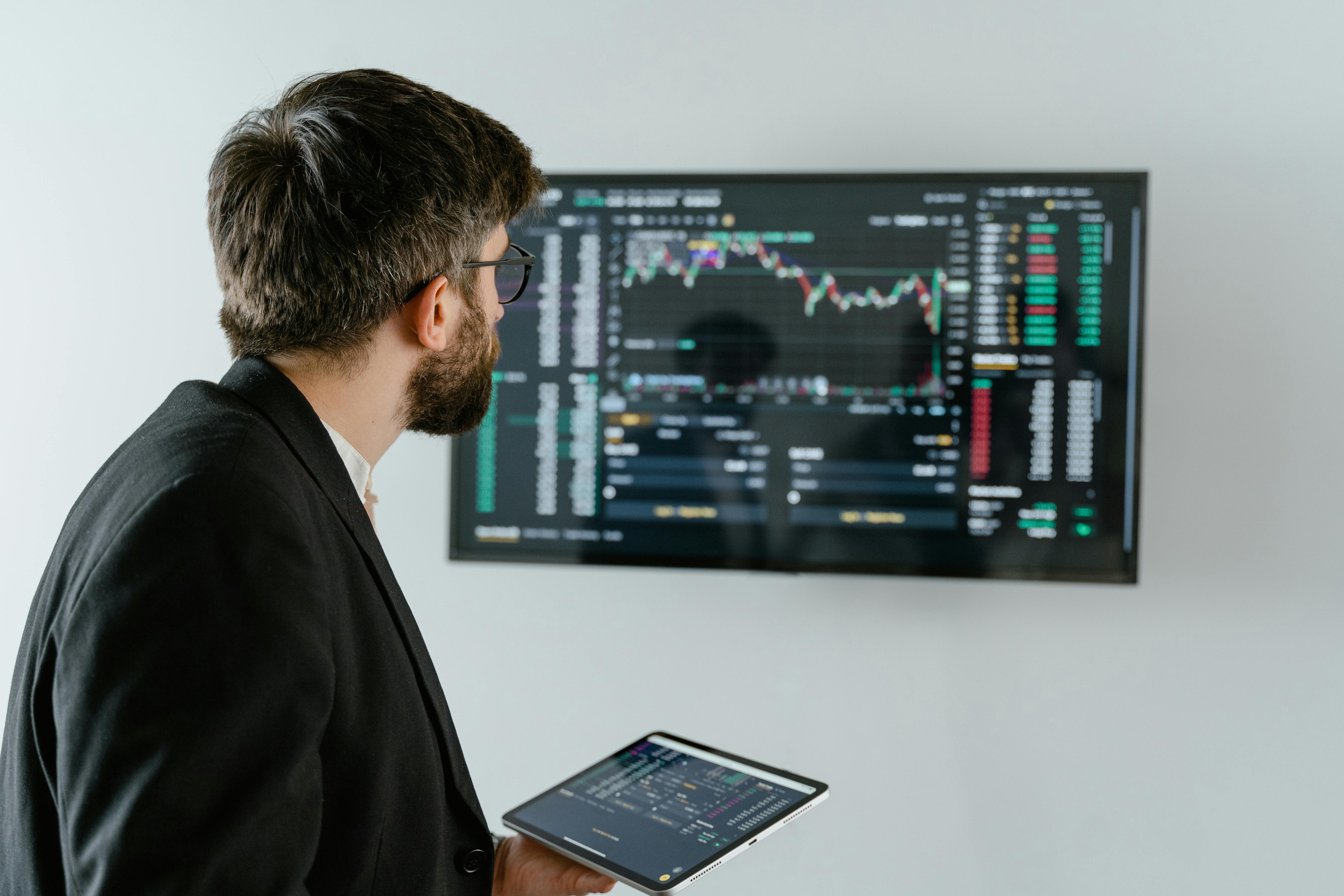 Free Man in Black Suit Holding a Digital Tablet and Looking At Data On Screen Stock Photo