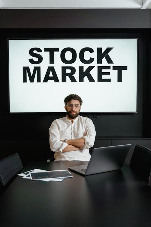 Free A Businessman in White Dress Shirt Sitting By the Table With Arms Crossed Stock Photo