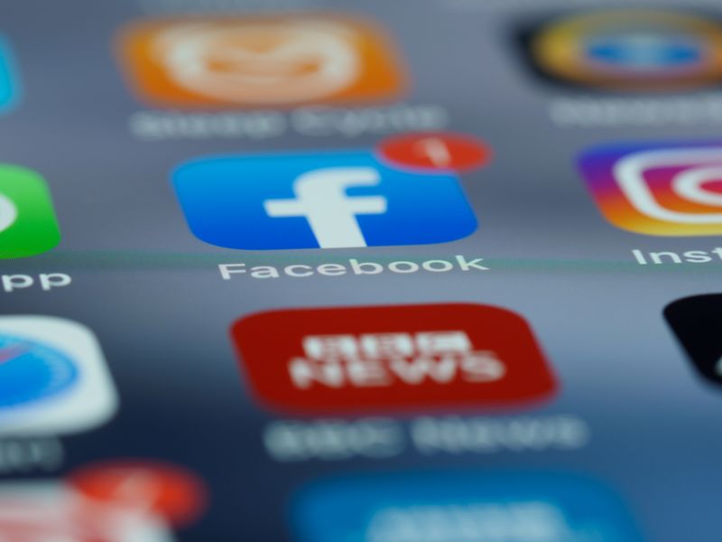 Close-up of smartphone screen displaying various social media app icons including Facebook