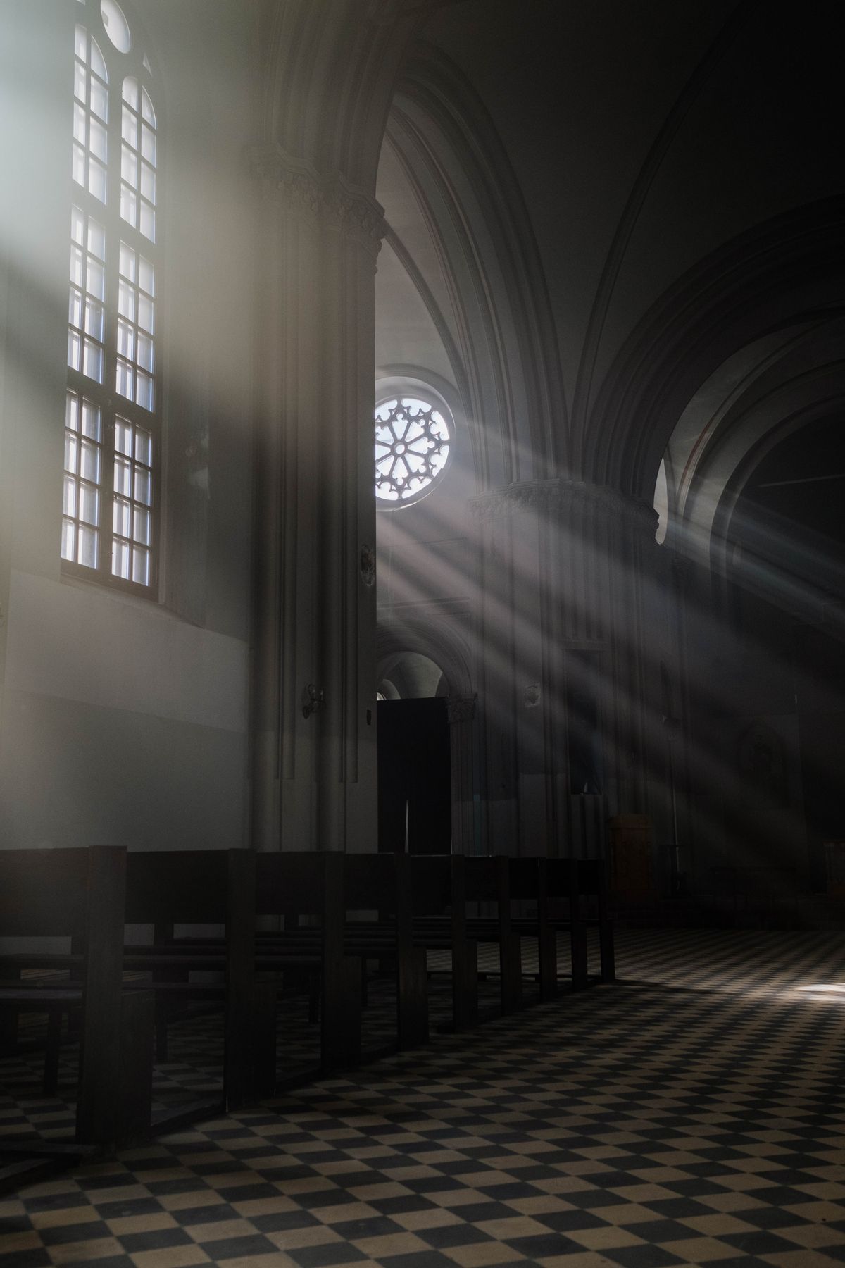 Interior de igreja com bancos vazios e luz do sol entrando pelas janelas