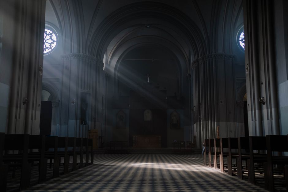 Gothic cathedral interior with sunlight streaming through arched windows onto the altar